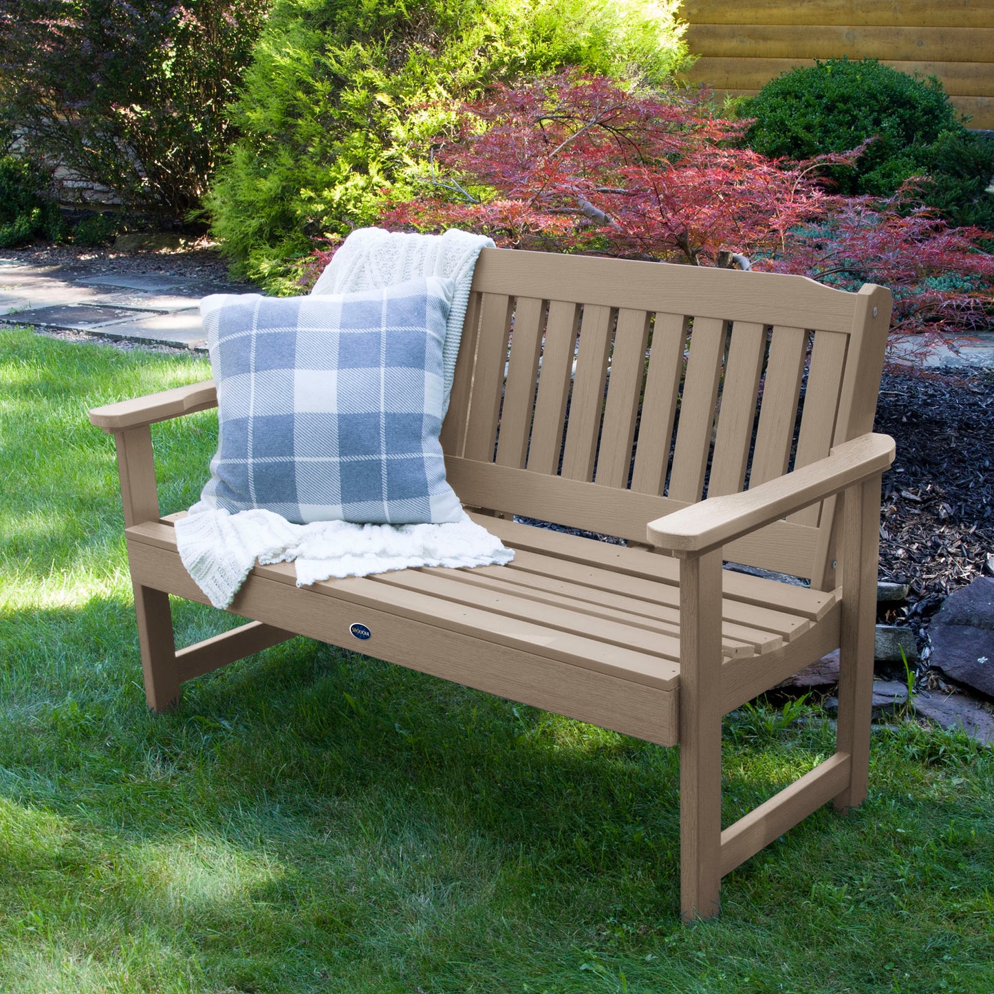 4ft light brown Blue Ridge garden bench on grass with blanket and pillow