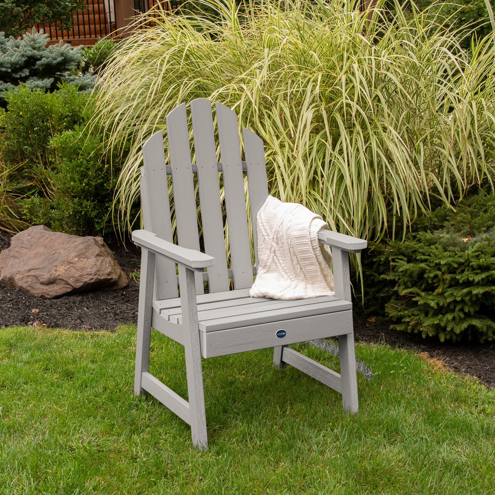 Light gray Lighthouse Garden Chair on grass in front of bushes