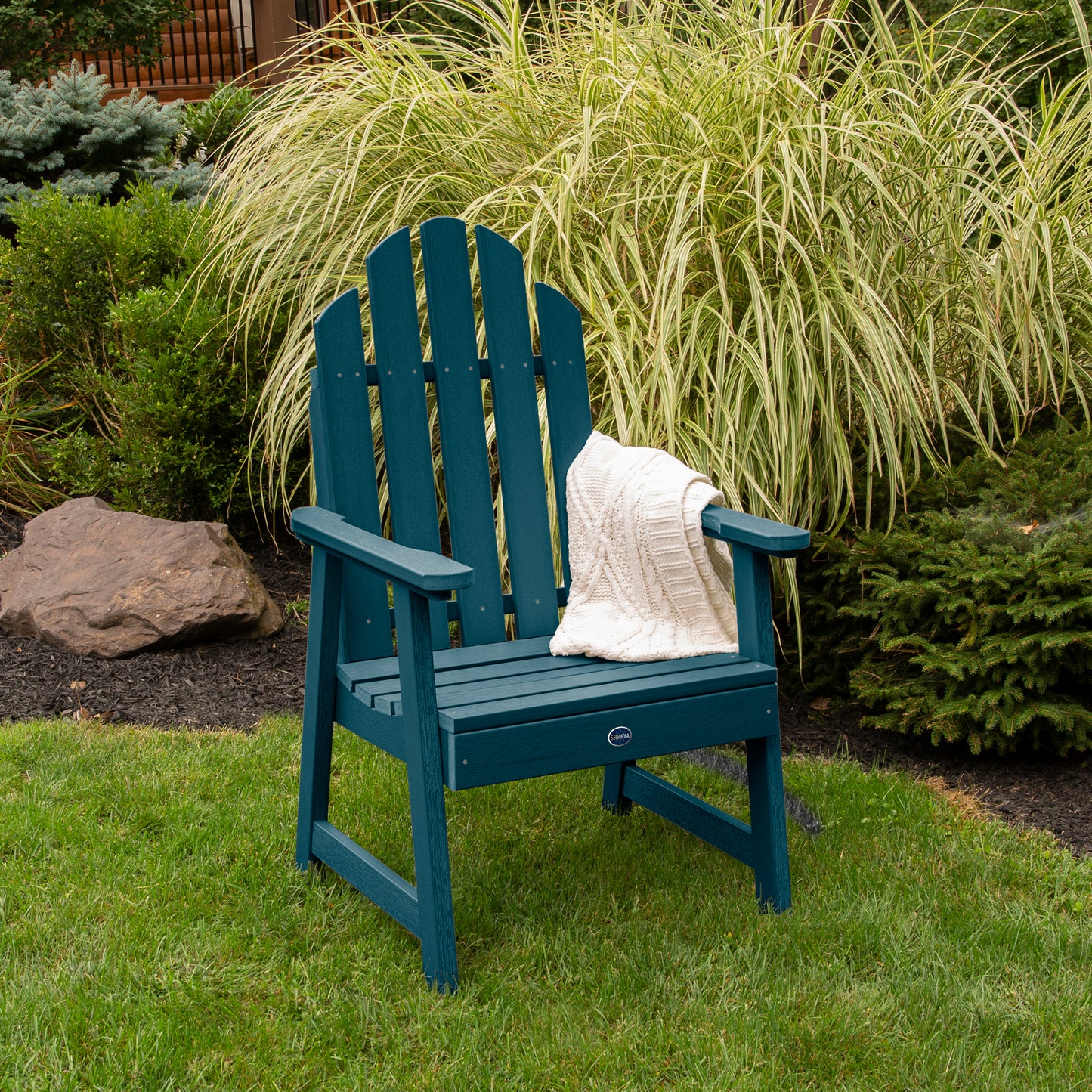Light blue Lighthouse Garden Chair on grass in front of bushes