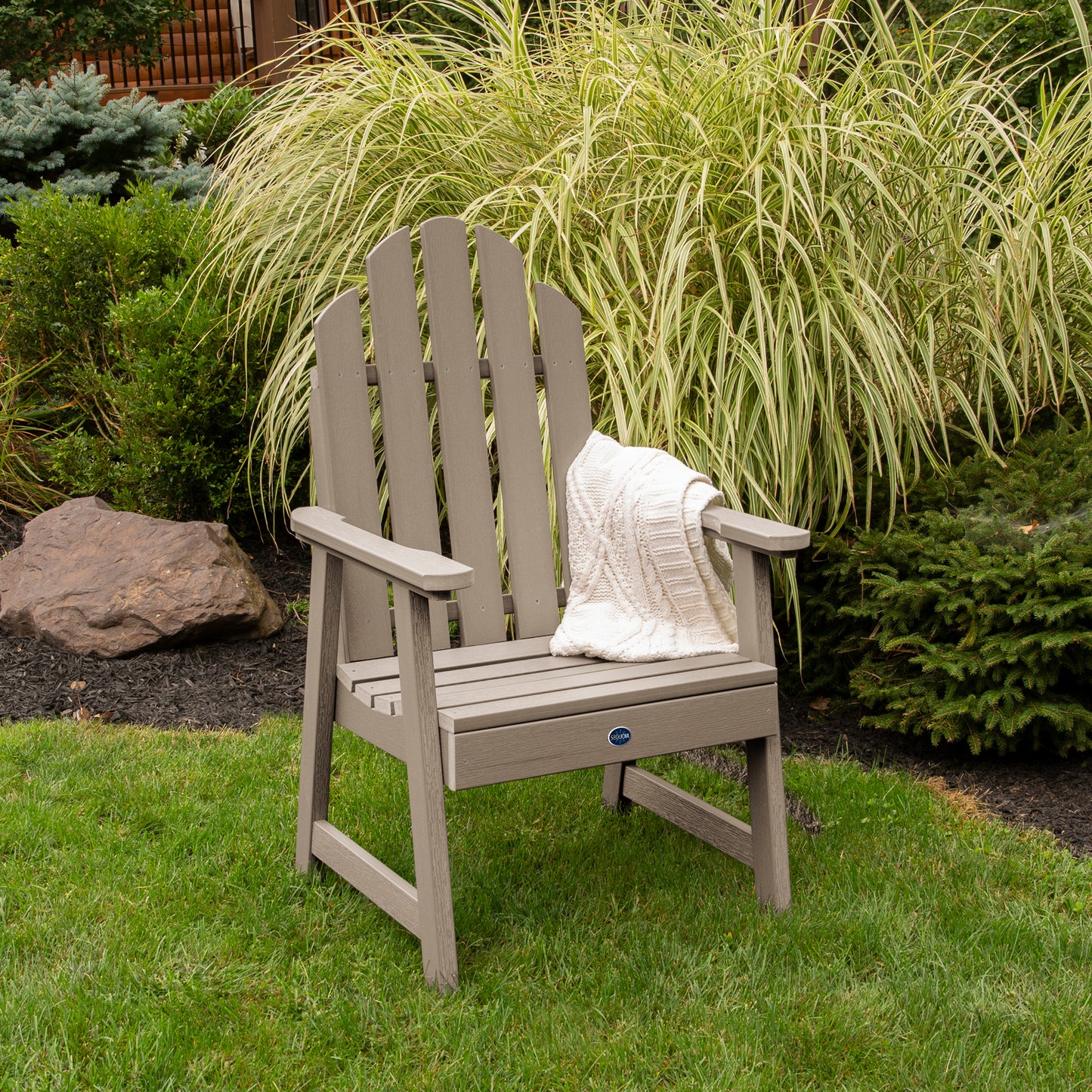 Light brown Lighthouse Garden Chair on grass in front of bushes