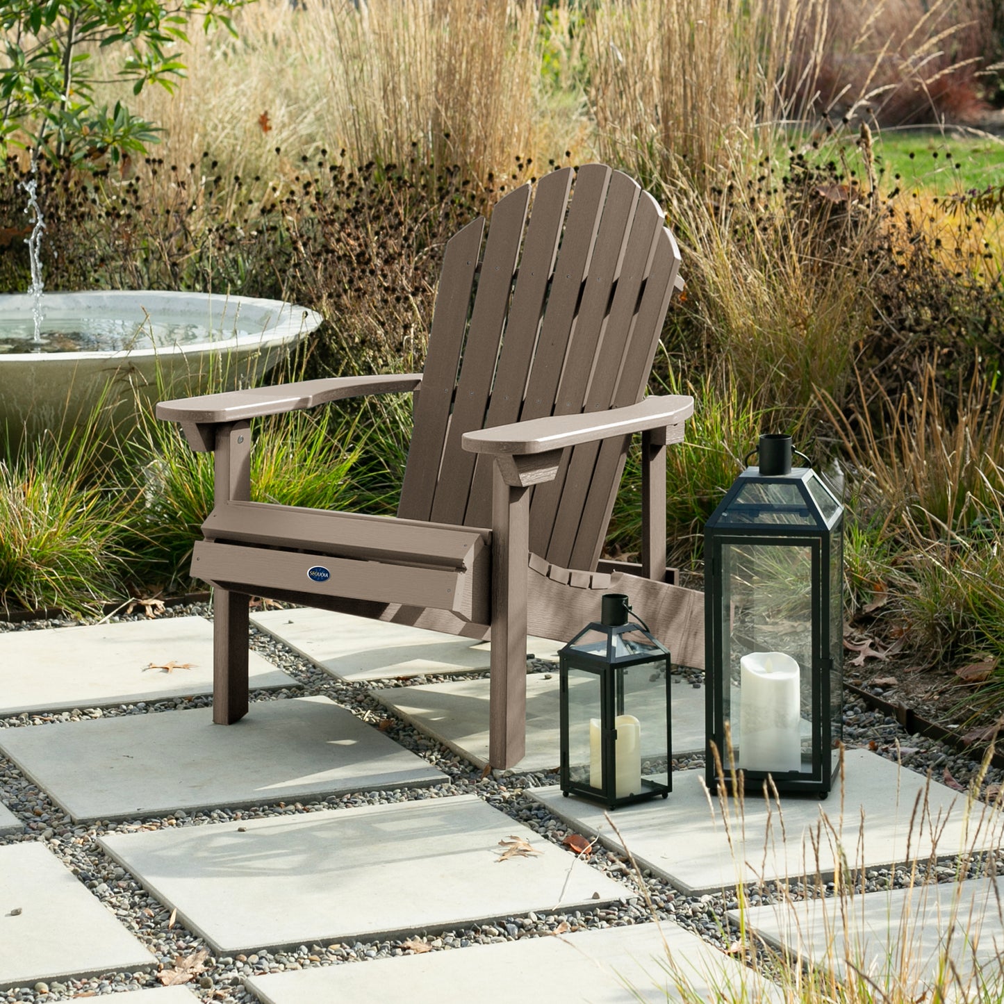 Light brown Horizon Adirondack chair on stone next to lanterns
