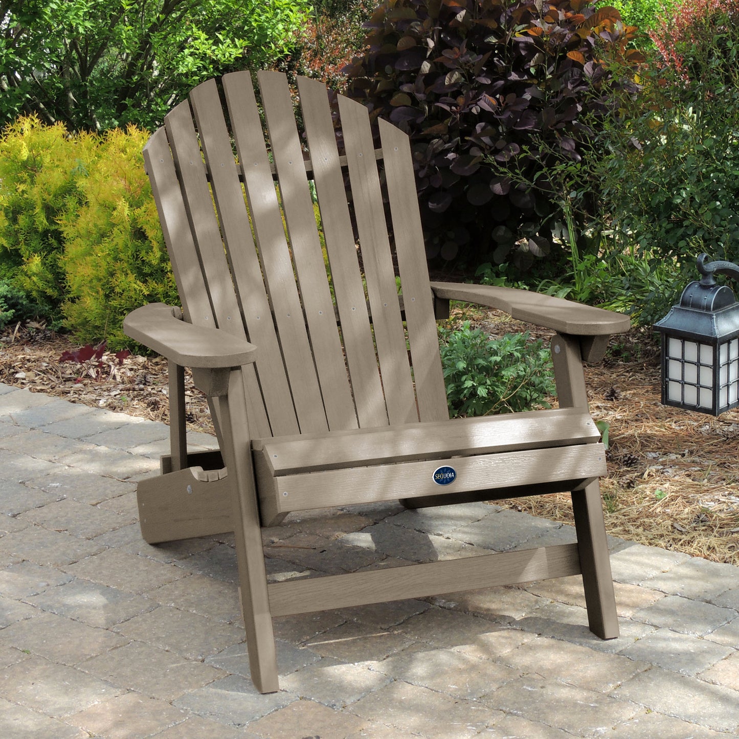 Light brown Horizon King-sized Adirondack chair on stone with trees in background