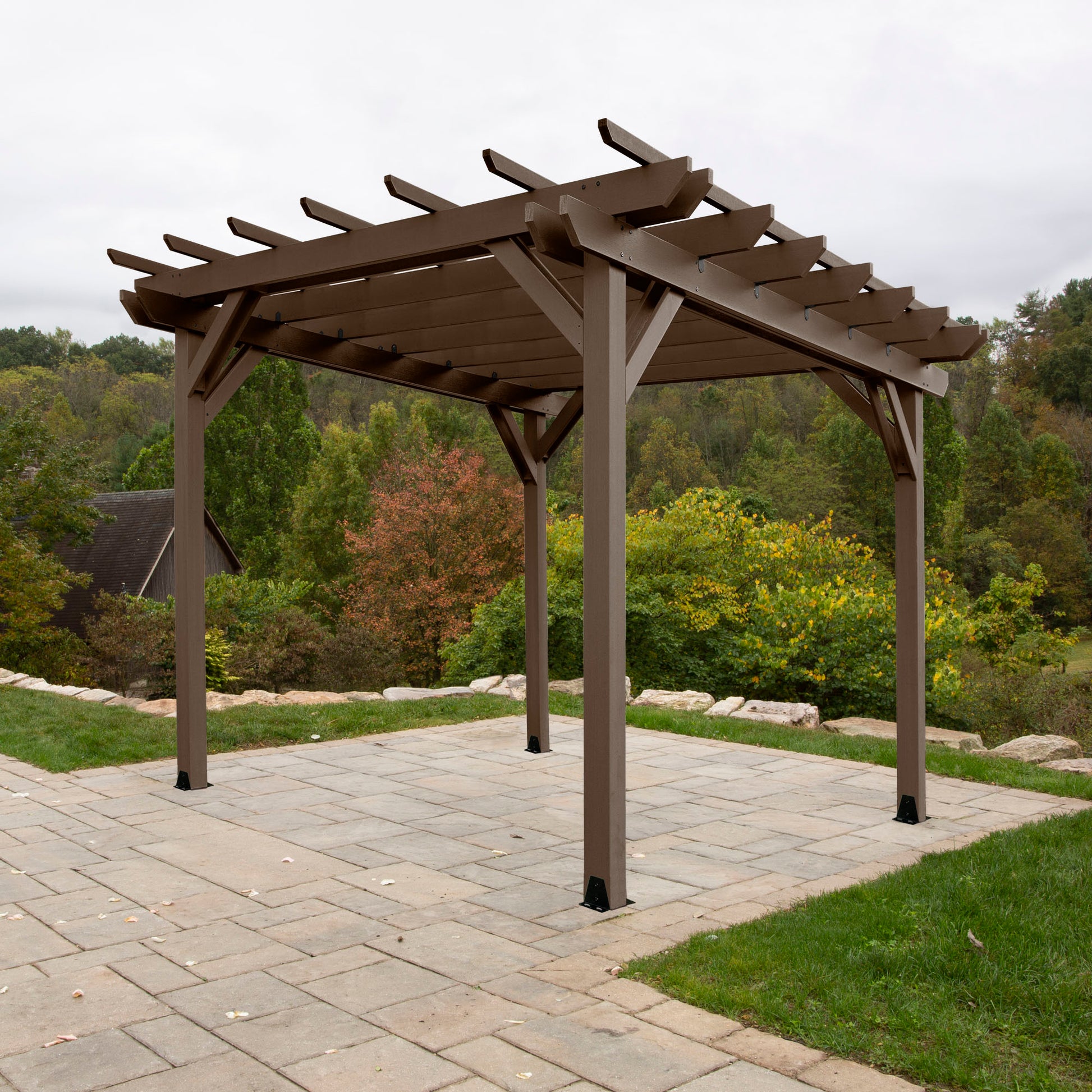 Brown St. Clair 12 x 12 Pergola on stone patio with trees in background