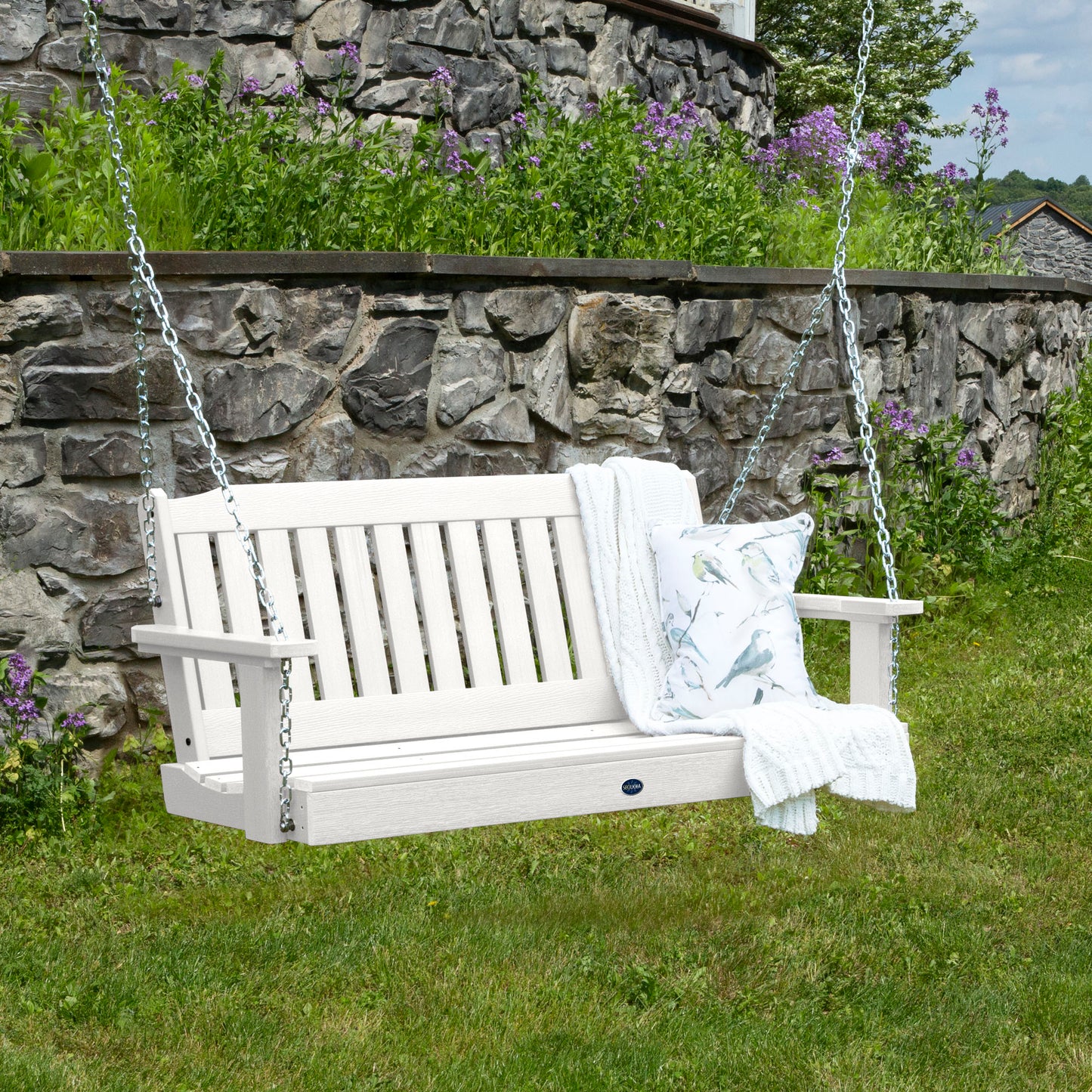 White 4ft Blue Ridge porch swing with blanket and pillow and stone wall in background