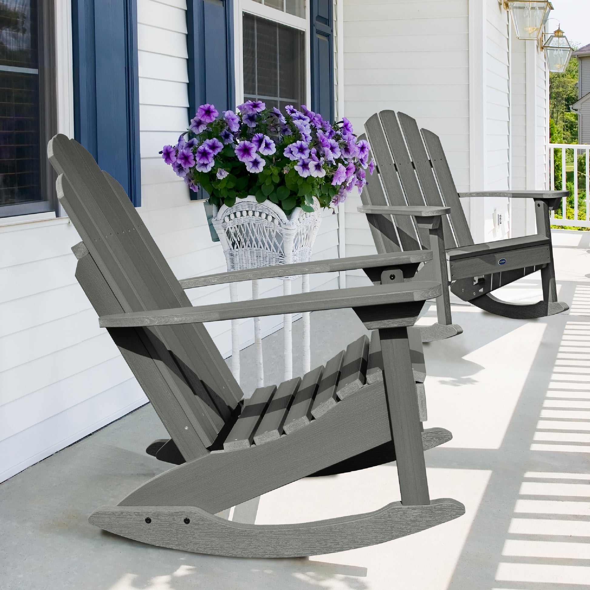 Two gray Lighthouse Adirondack rocking chairs on front porch with flowers