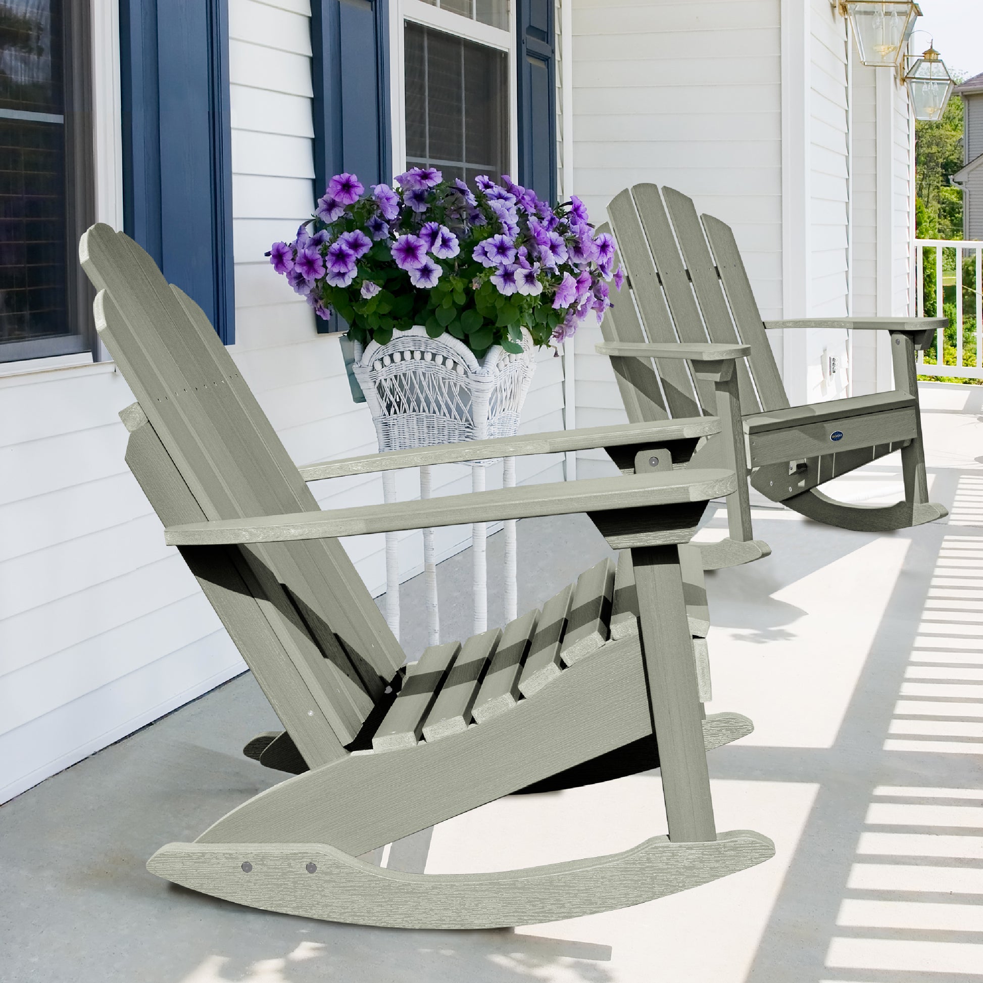 Two light green Lighthouse Adirondack rocking chairs on front porch with flowers