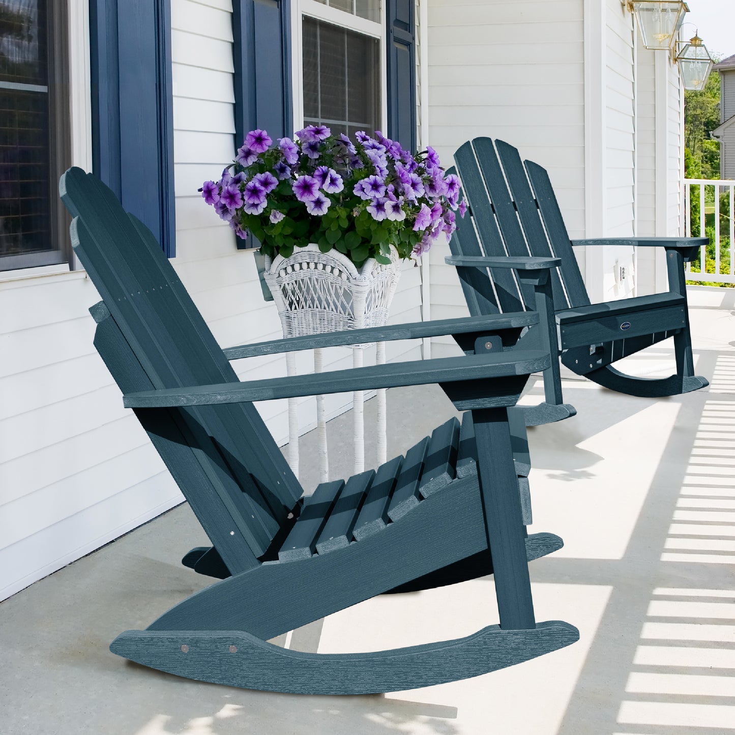 Two light blue Lighthouse Adirondack rocking chairs on front porch with flowers