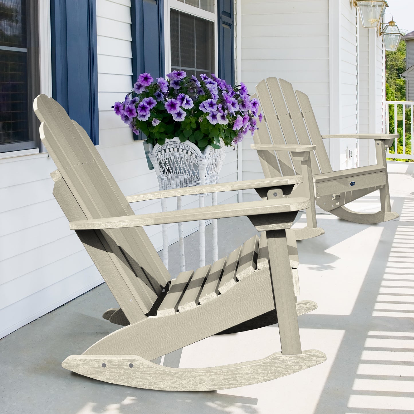 Two whitewash Lighthouse Adirondack rocking chairs on front porch with flowers