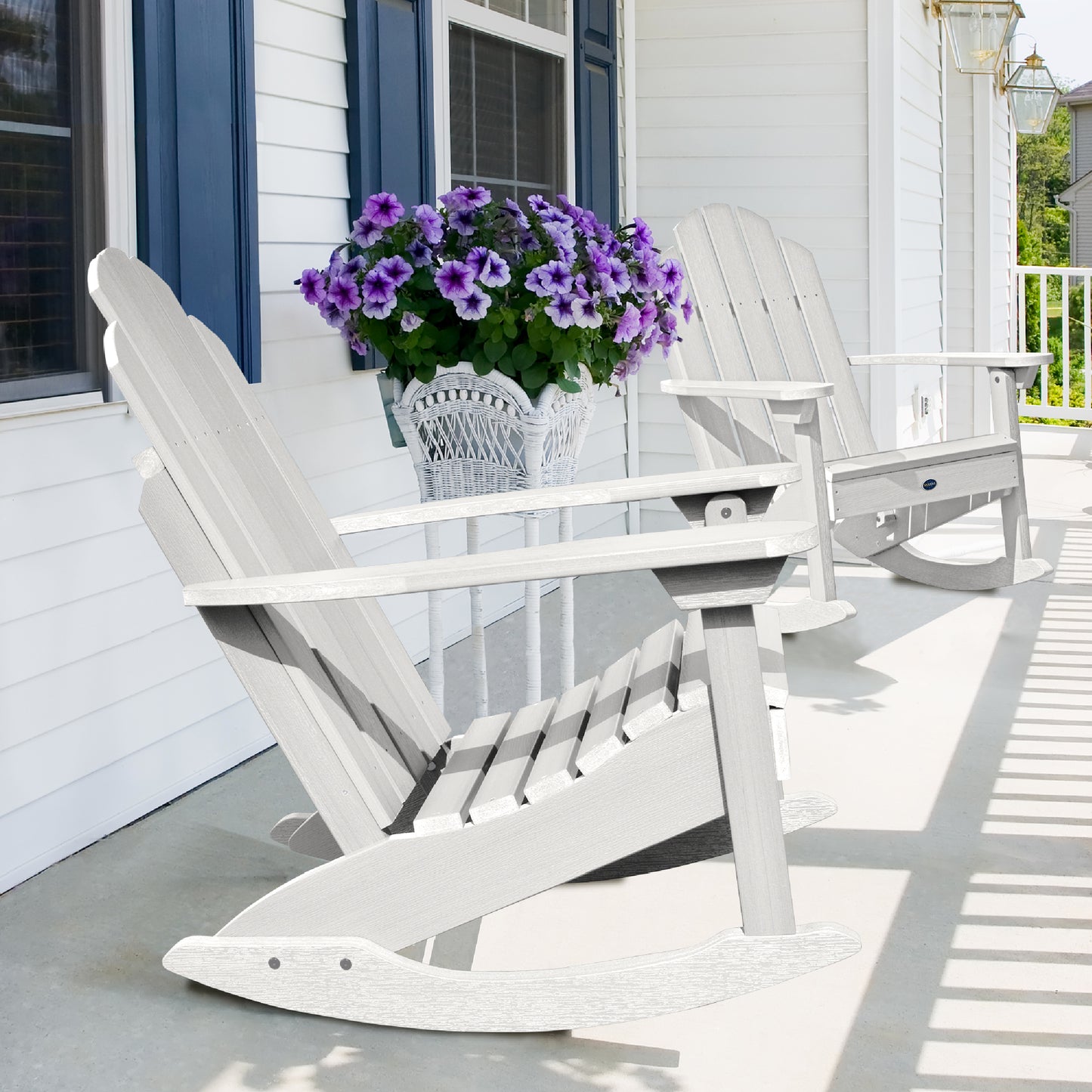 Two white Lighthouse Adirondack rocking chairs on front porch with flowers