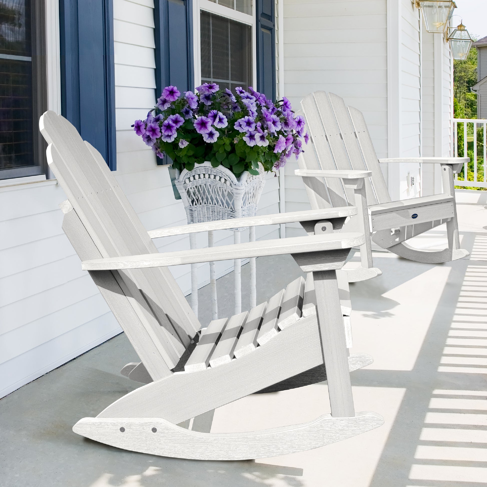 Two white Lighthouse Adirondack rocking chairs on front porch with flowers