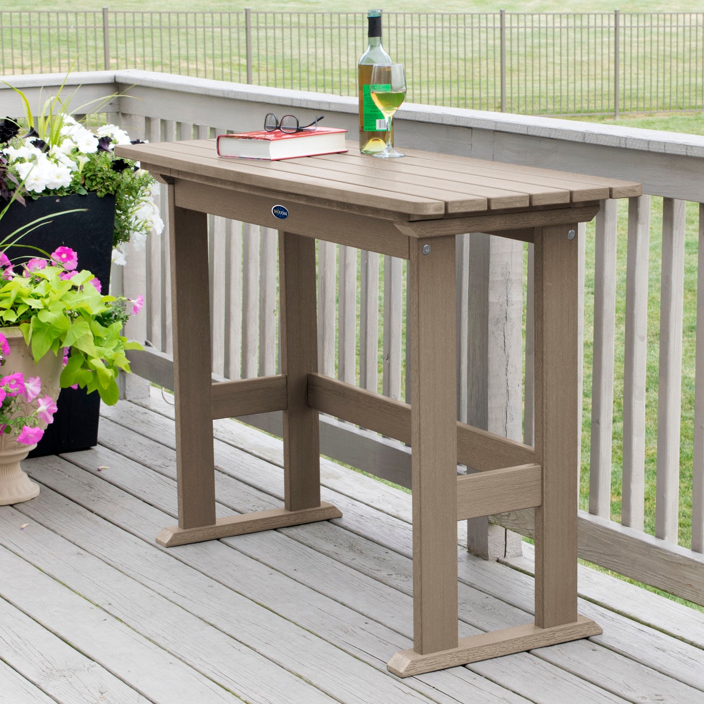 Light brown Blue Ridge counter height balcony table on tan wooden deck with book and wine