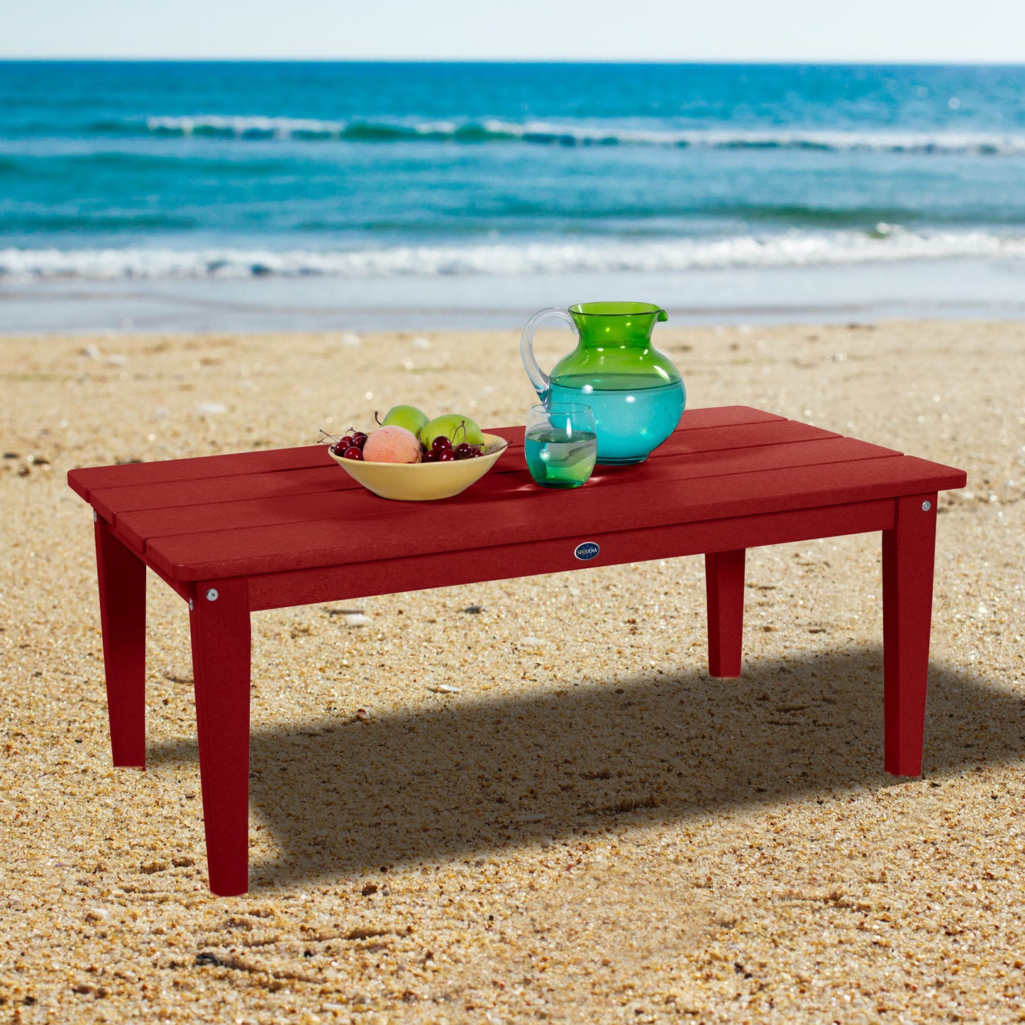 Red Sunrise Coast conversation table on beach with water pitcher and fruit