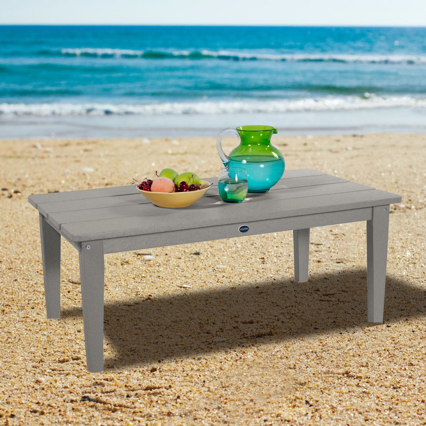 Gray Sunrise Coast conversation table on beach with water pitcher and fruit
