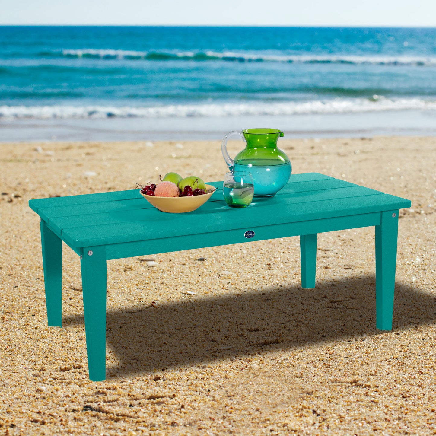 Blue Sunrise Coast conversation table on beach with water pitcher and fruit