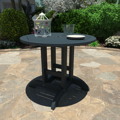 Dark Blue 36” diameter dining height table with lantern, plates, and glasses