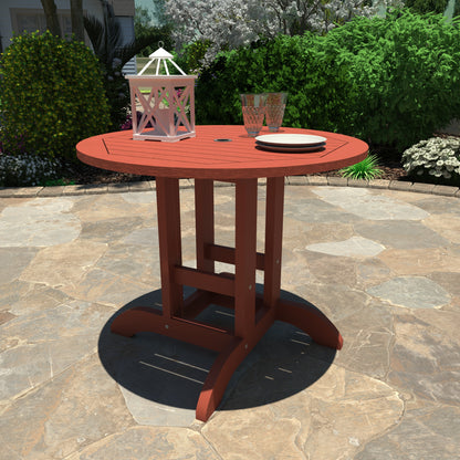 Red 36” diameter dining height table with lantern, plates, and glasses