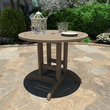Light brown 36” diameter dining height table with lantern, plates, and glasses