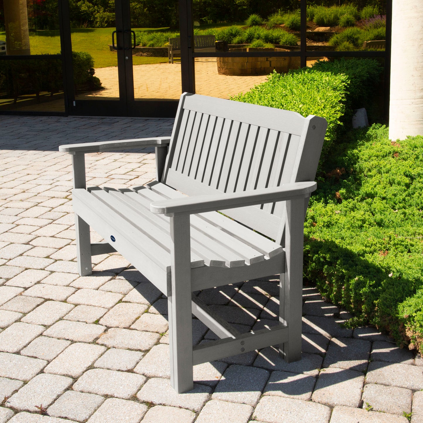 Light gray 4ft Blue Ridge Commercial Garden Bench on stone pathway