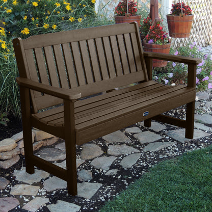 5ft brown Blue Ridge garden bench on stone pathway with flowers in background 
