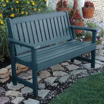 5ft light blue Blue Ridge garden bench on stone pathway with flowers in background 
