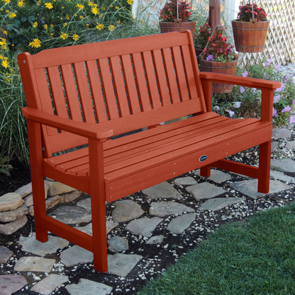 5ft red Blue Ridge garden bench on stone pathway with flowers in background 