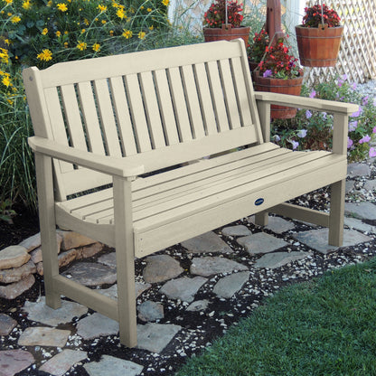 5ft Whitewash Blue Ridge garden bench on stone pathway with flowers in background 