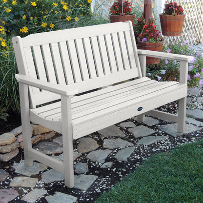 5ft white Blue Ridge garden bench on stone pathway with flowers in background 