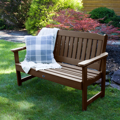4ft brown Blue Ridge garden bench on grass with blanket and pillow