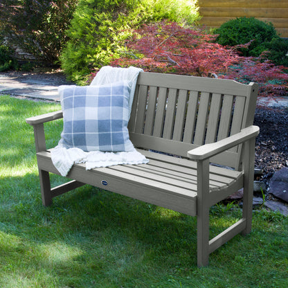 4ft light gray Blue Ridge garden bench on grass with blanket and pillow