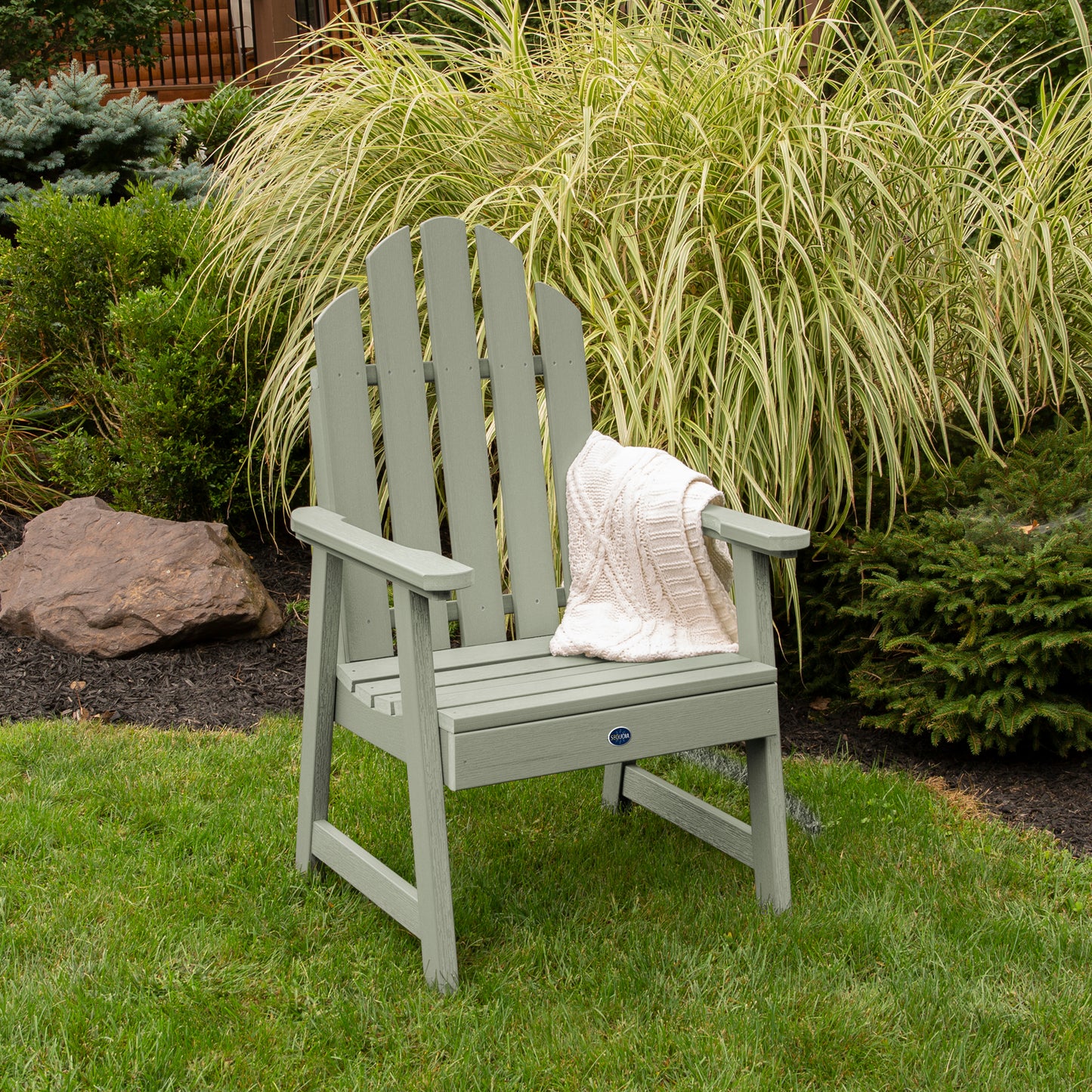 Light green Lighthouse Garden Chair on grass in front of bushes