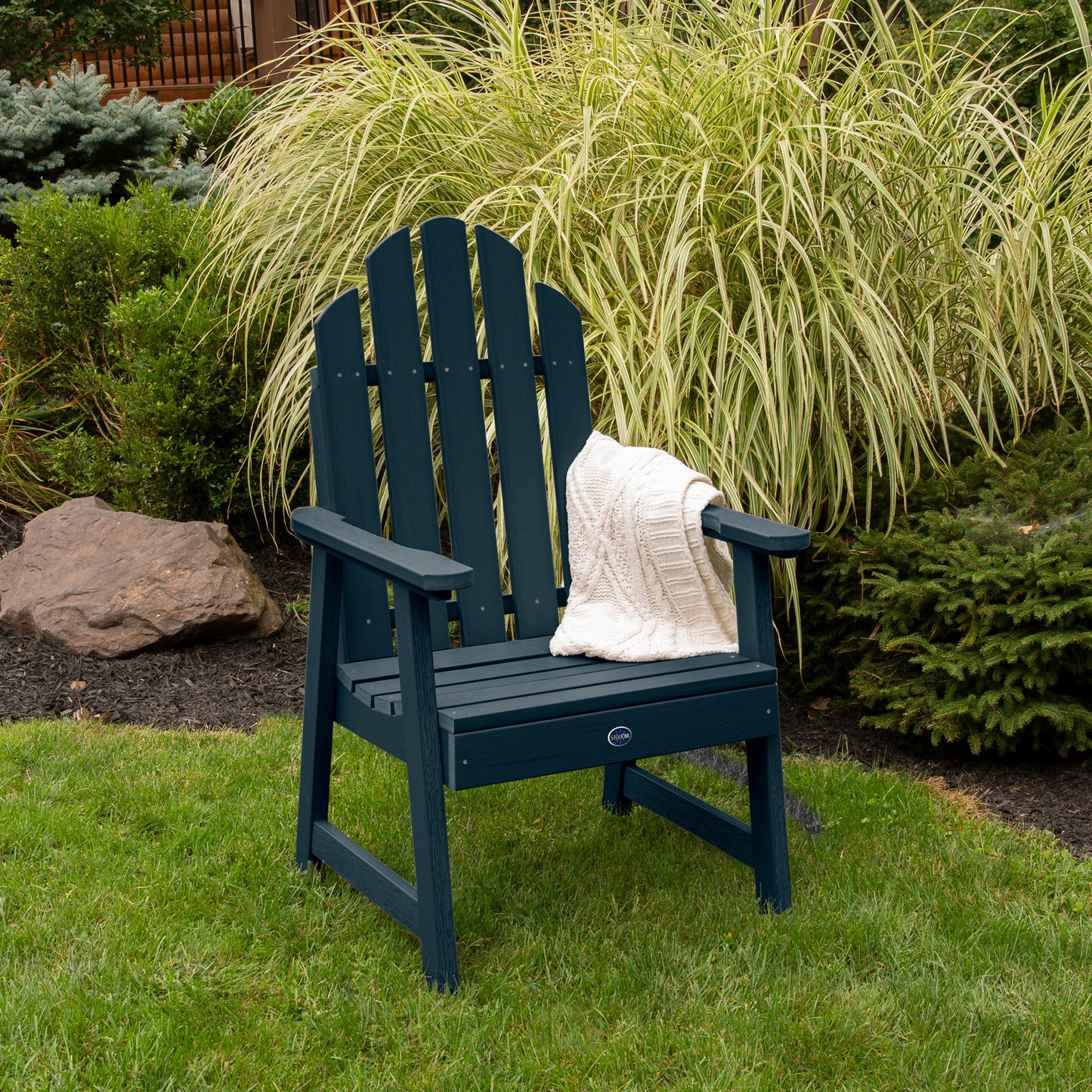 Dark blue Lighthouse Garden Chair on grass in front of bushes