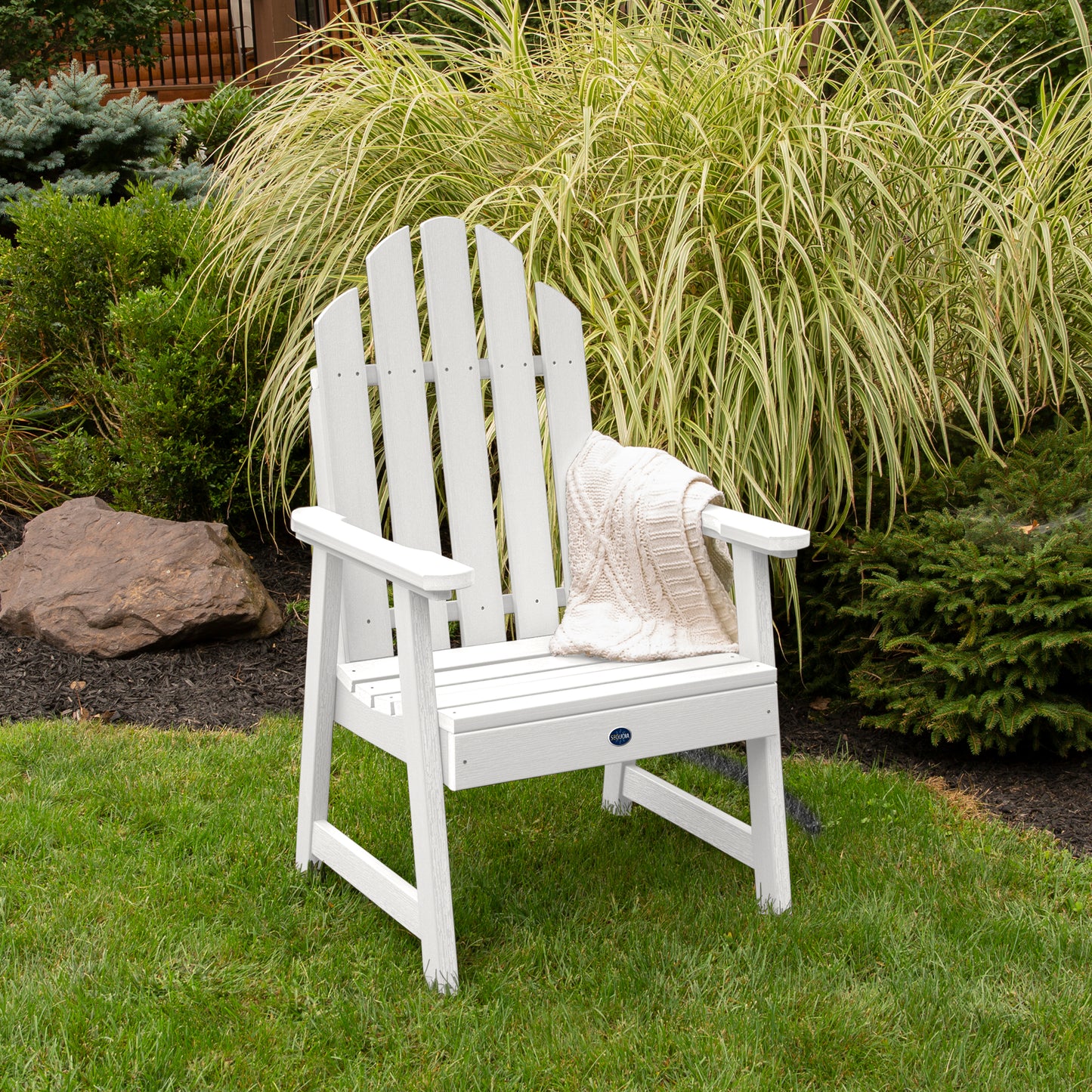 White Lighthouse Garden Chair on grass in front of bushes