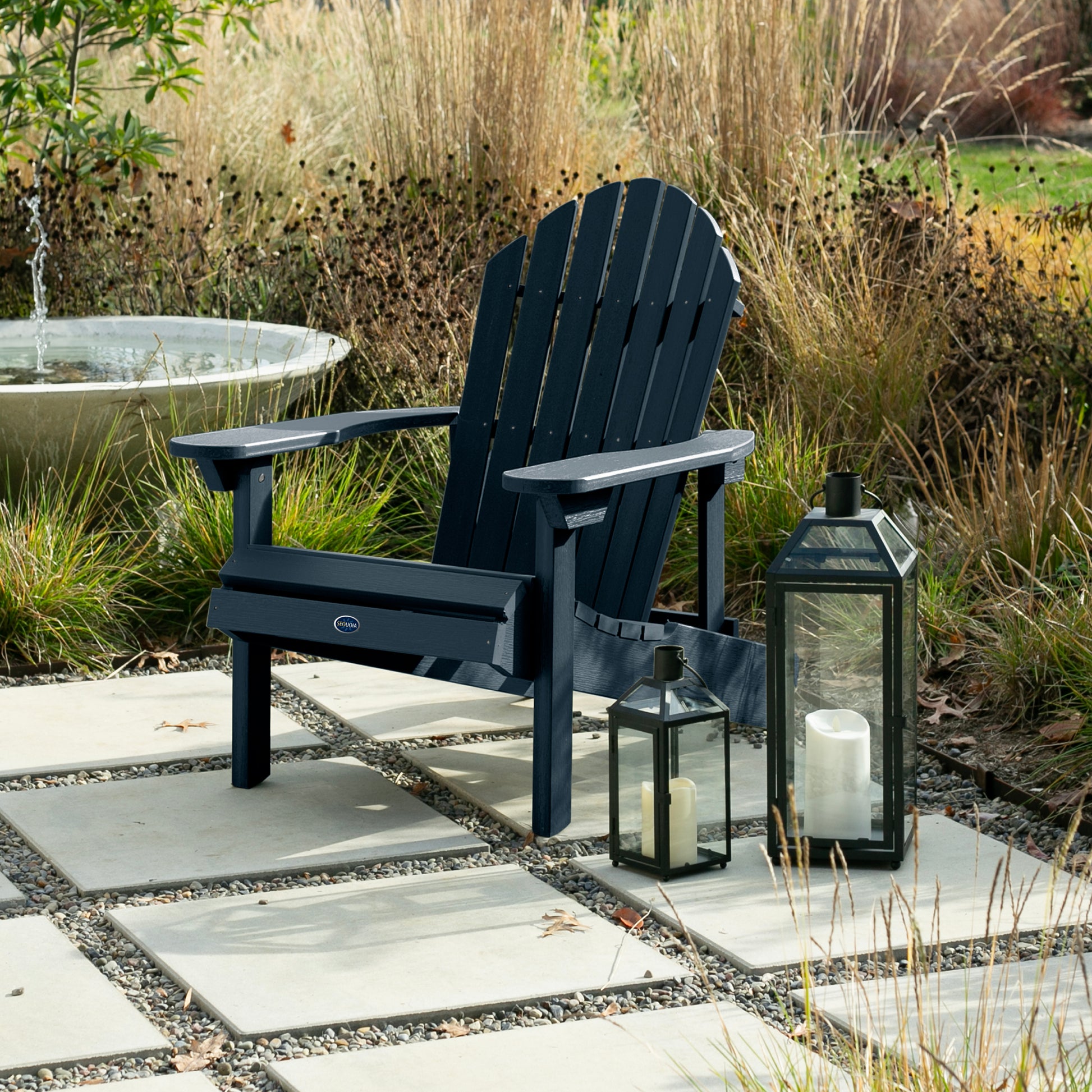 Dark blue Horizon Adirondack chair on stone next to lanterns