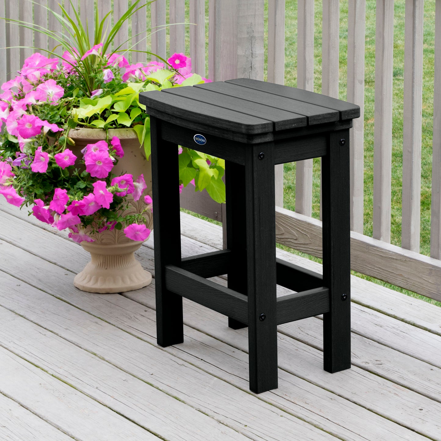 Black Blue Ridge counter height stool on tan wooden deck next to flowers