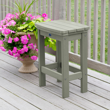 Light green Blue Ridge counter height stool on tan wooden deck next to flowers