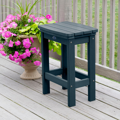 Dark blue Ridge counter height stool on tan wooden deck next to flowers