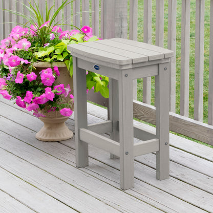 Light gray Blue Ridge counter height stool on tan wooden deck next to flowers