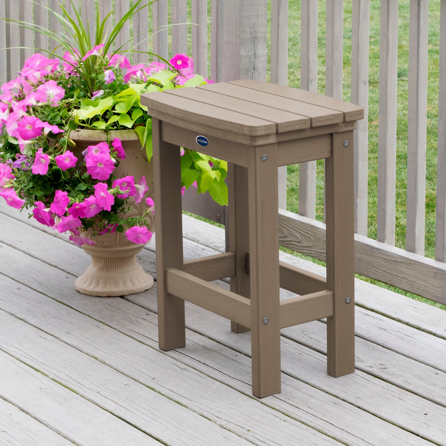 Light brown Blue Ridge counter height stool on tan wooden deck next to flowers