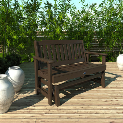 4ft brown Blue Ridge glider bench on wooden patio with plants in background 