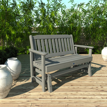 4ft light gray Blue Ridge glider bench on wooden patio with plants in background 