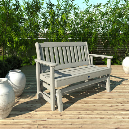 4ft light gray Blue Ridge glider bench on wooden patio with plants in background 