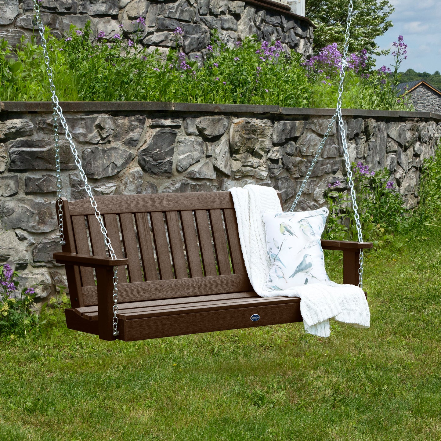 Brown 4ft Blue Ridge porch swing with blanket and pillow and stone wall in background