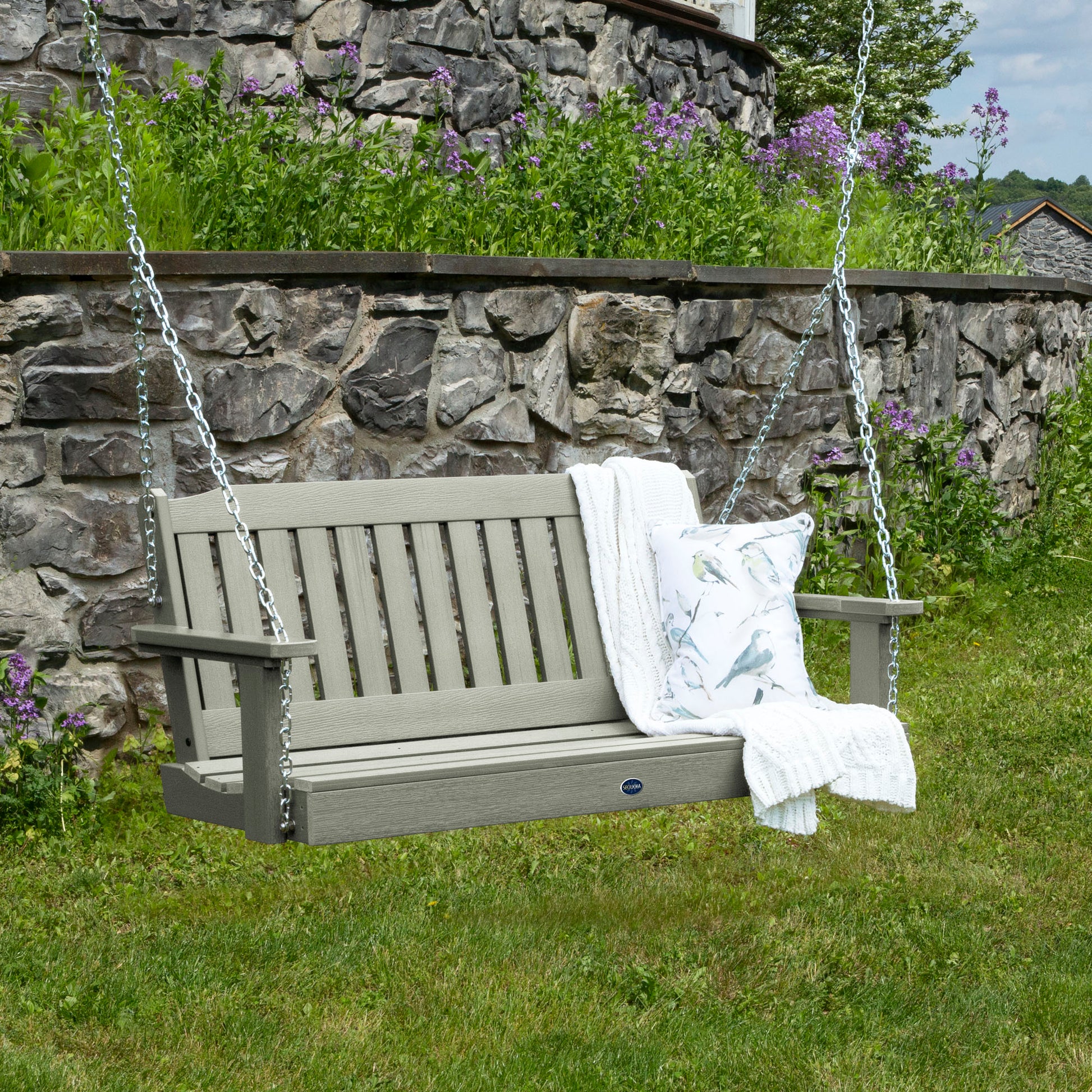 Light green 4ft Blue Ridge porch swing with blanket and pillow and stone wall in background