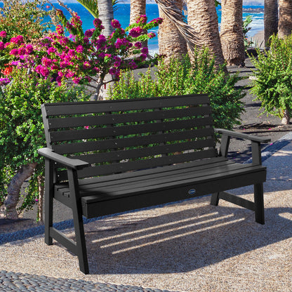 Black Sunrise Coast 5ft bench in front of flowers on walkway