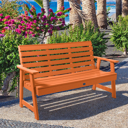 Orange Sunrise Coast 5ft bench in front of flowers on walkway