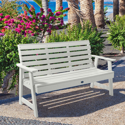 White Sunrise Coast 5ft bench in front of flowers on walkway