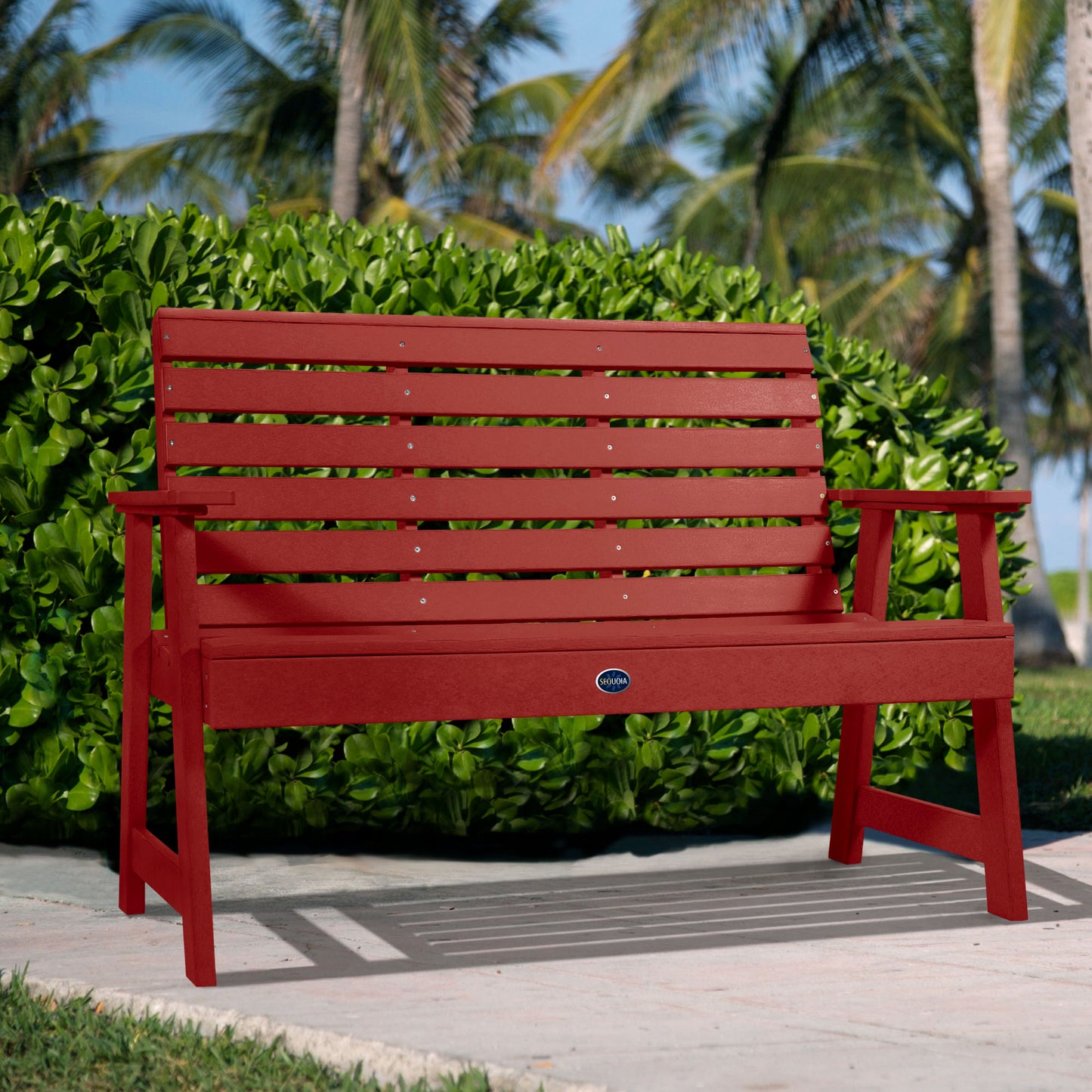 Red Sunrise Coast 4ft bench in front of bush on walkway