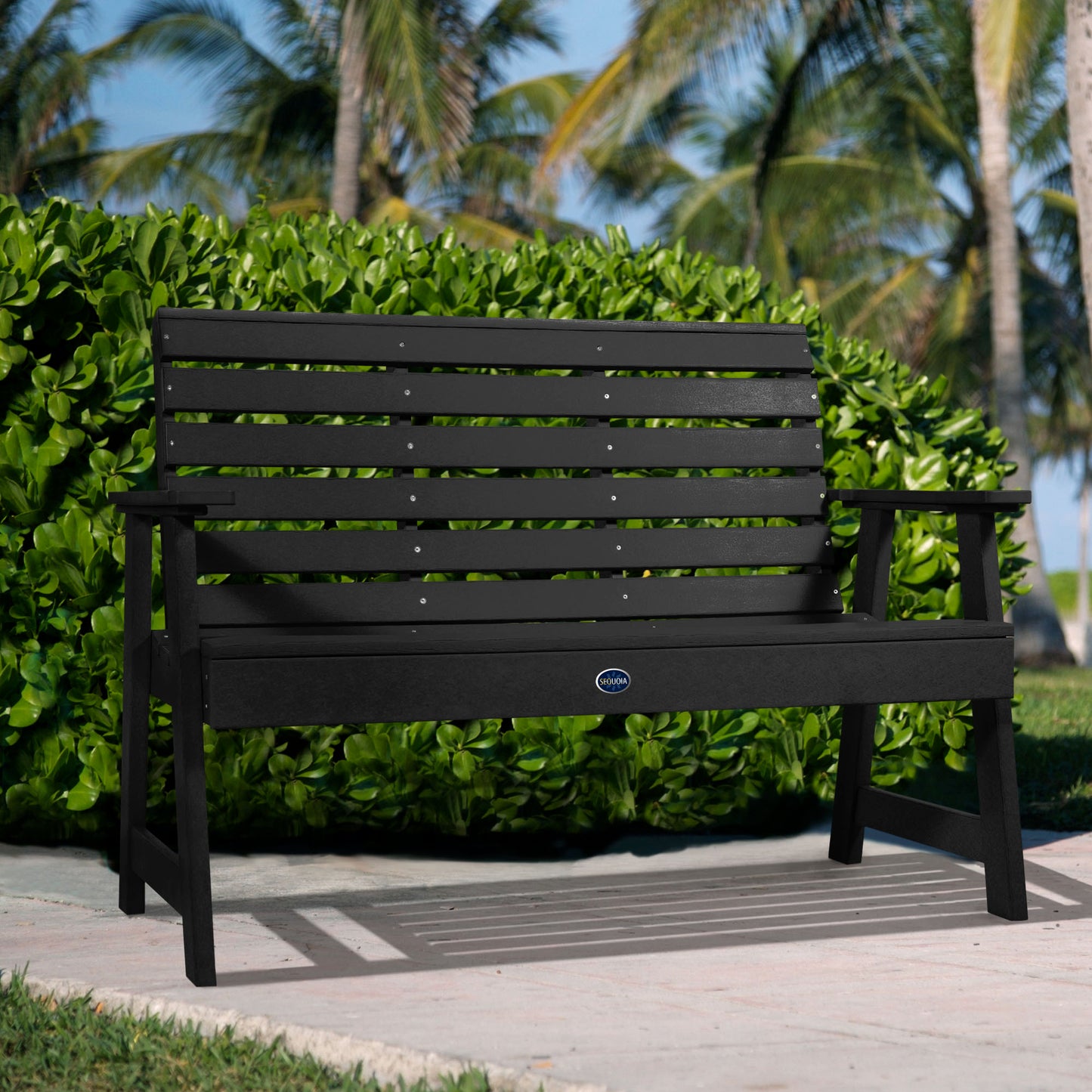 Black Sunrise Coast 4ft bench in front of bush on walkway