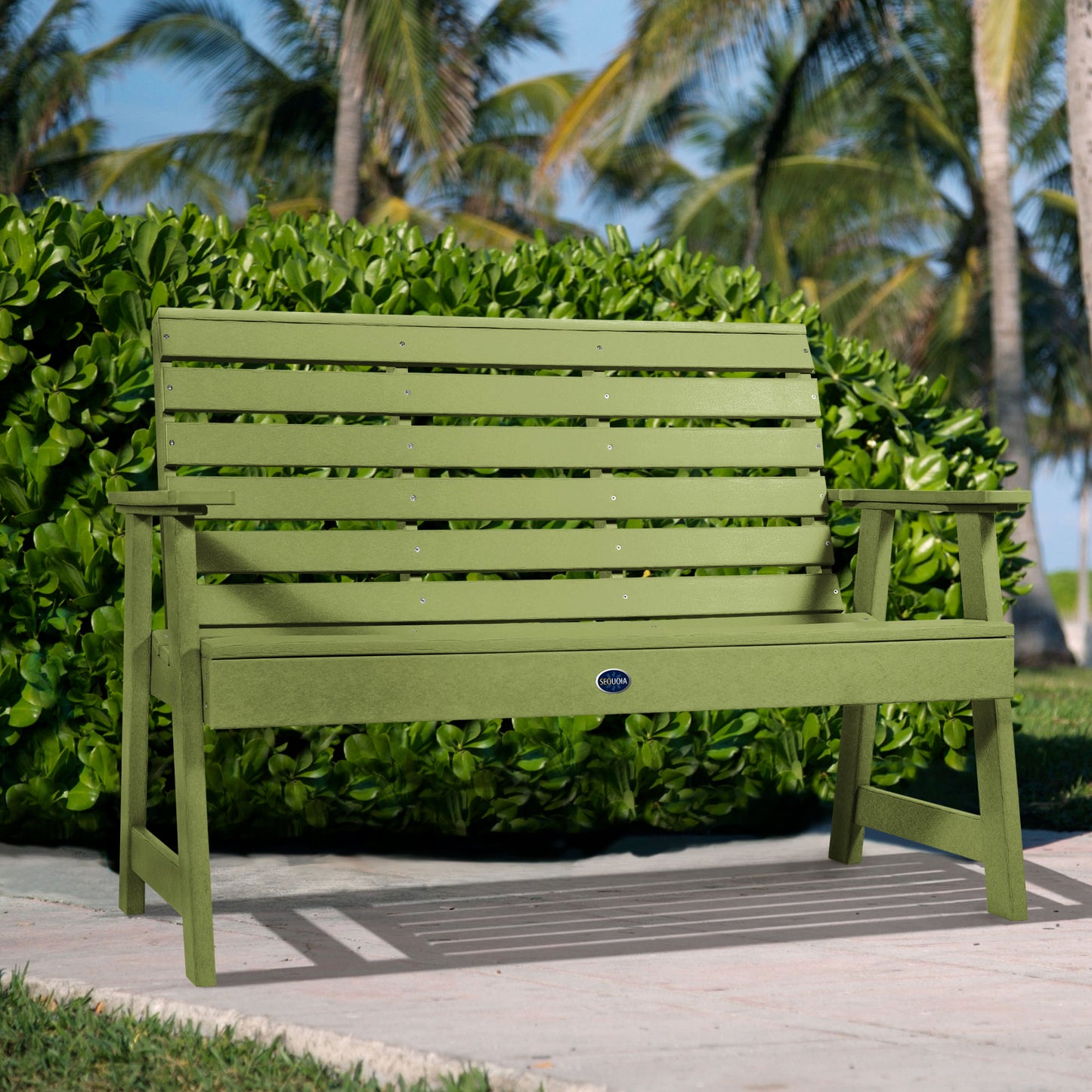 Green Sunrise Coast 4ft bench in front of bush on walkway