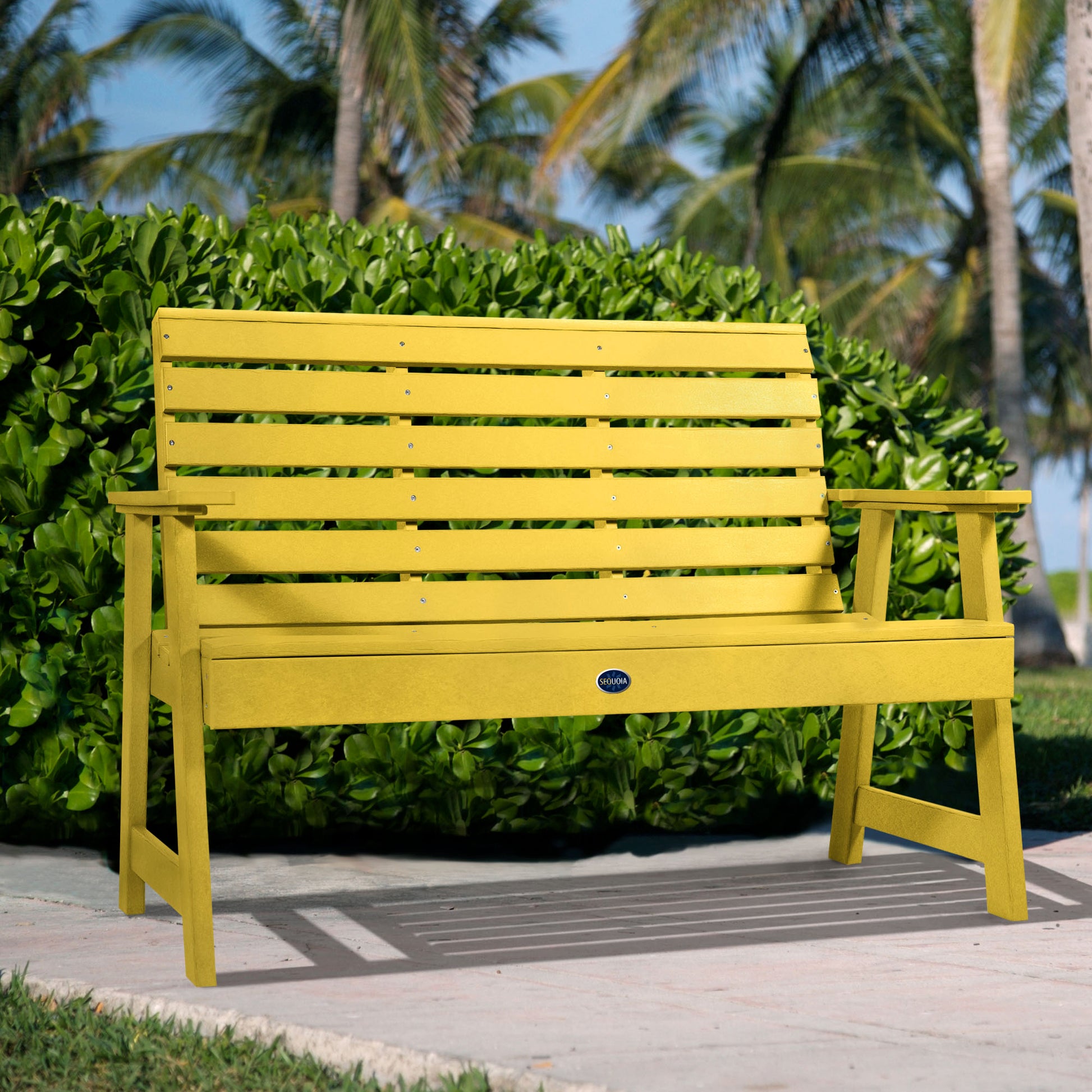 Yellow Sunrise Coast 4ft bench in front of bush on walkway